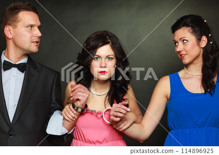 Wife and husband in handcuffs woman standing behind Wife and husband in handcuffs woman standing behind 114896925