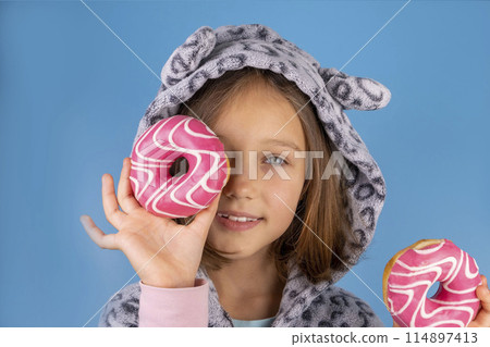 girl in kigurumi or pajamas with donuts in place of the eyes on a pink background. High quality photo girl in kigurumi or pajamas with donuts in place of the eyes on a pink background. High quality photo 114897413