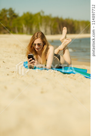 Woman in bikini sunbathing and relaxing on beach 114897712
