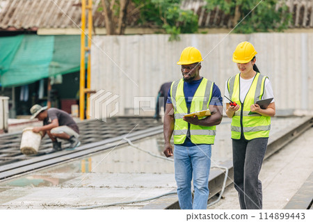 Engineer smart women working contact with African black worker in Precast concrete casting manufacturing company site inspector 114899443