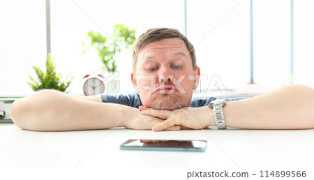 Man with funny facial expression staring at cellphone 114899566