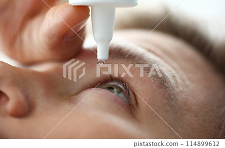 Male hand putting liquid drops in his eye solving vision problem 114899612