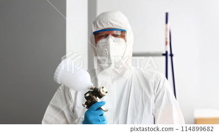 Workman hold in arm airbrush gun wearing protective suit 114899682