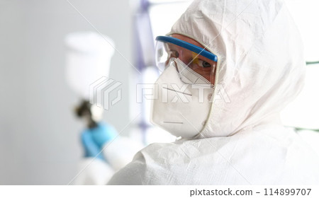 Man with pulverizer in hands look in camera thru protective glasses Man with pulverizer in hands look in camera thru protective glasses 114899707
