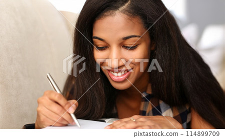 Smiling black woman write story in notebook 114899709