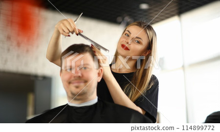 Female Hairdresser Combing Male Client in Salon 114899772