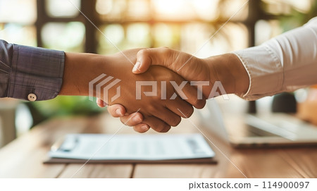 Handshake over documents on a table signifies a successful business deal. 114900097