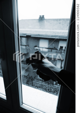 Gunman holding pistole in window Gunman holding pistole in window 114900382