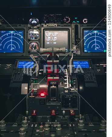 Cockpit view of an airplane during a night-time flight with illuminated instrument panels 114900649