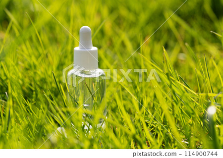 clear serum bottle in lush green grass 114900744
