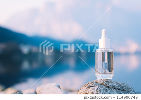 Clear dropper bottle with lake and mountains in background Clear dropper bottle with lake and mountains in background 114900749