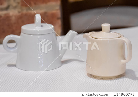 Two teapots on table with brick wall background 114900775