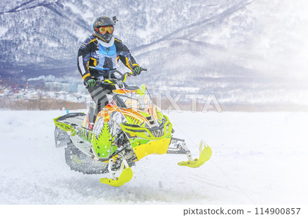 Athlete on a snowmobile moving in the winter forest on the competition Snow Way in the mountains of Kamchatka Athlete on a snowmobile moving in the winter forest on the competition Snow Way in the mountains of Kamchatka 114900857