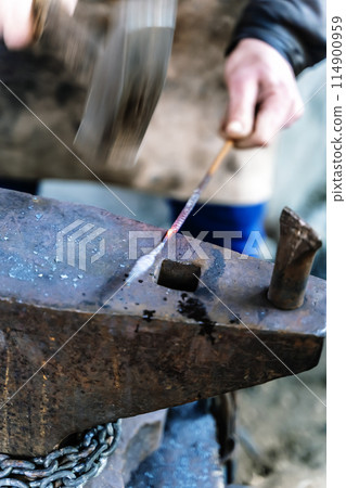 Blacksmith in a forge at work on an anvil. Hot metal forging 114900959