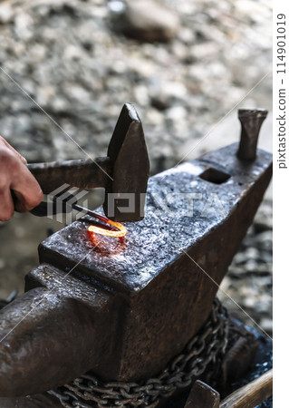 Blacksmith in a forge at work on an anvil. Hot metal forging 114901019