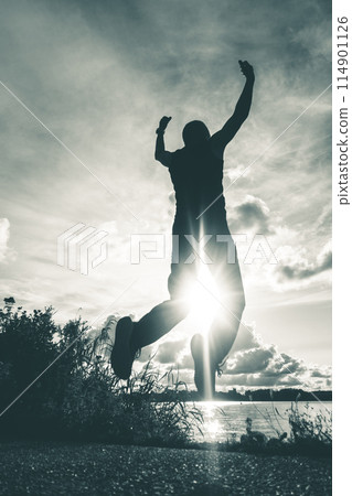 Man jumping by lake at sunset 114901126
