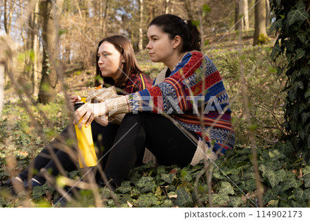 two young women with thermos in nature, in the forest two young women with thermos in nature, in the forest 114902173