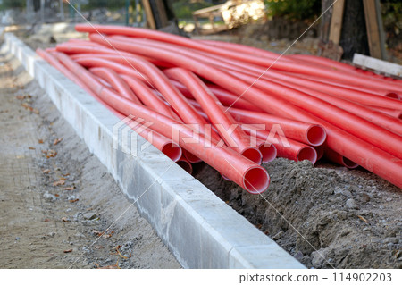 Red plastic utility pipes piled at a road repair site 114902203