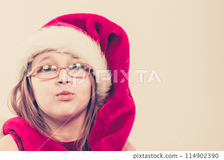 Girl in santa hat making silly face 114902390