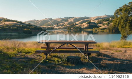 Serene Lakeside Picnic Spot: Wooden table/benches, scenic hills - perfect road trip pause. 114902536