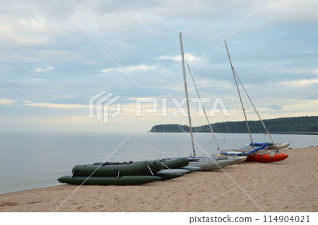 Catamarans with masts on lake shore. 114904021