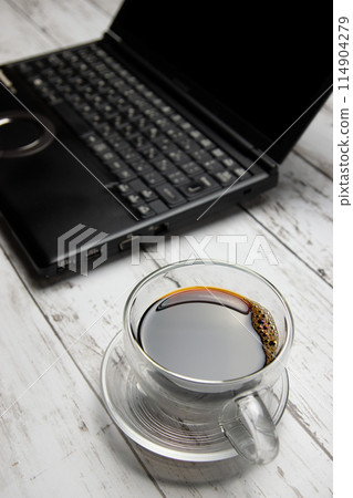 Glass coffee cup and laptop in vertical composition Glass coffee cup and laptop in vertical composition 114904279