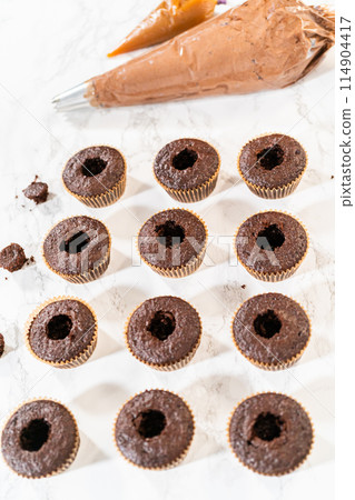 Each chocolate cupcake receives a generous filling of luscious caramel, adding an extra layer of flavor and indulgence. Each chocolate cupcake receives a generous filling of luscious caramel, adding an extra layer of flavor and indulgence. 114904417