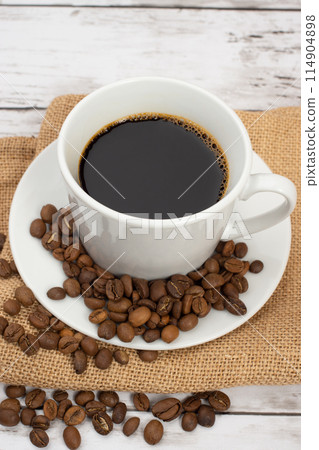 Burlap sack, coffee cup and coffee on a white wooden table 114904898