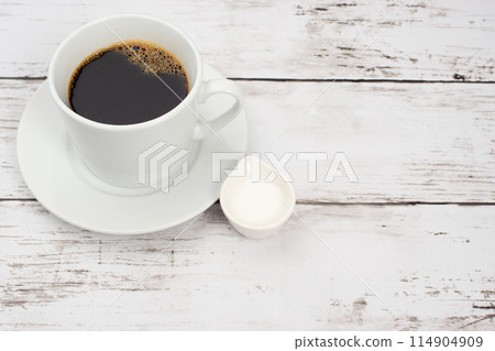 Coffee cup and coffee creamer placed on a white wooden table Coffee cup and coffee creamer placed on a white wooden table 114904909