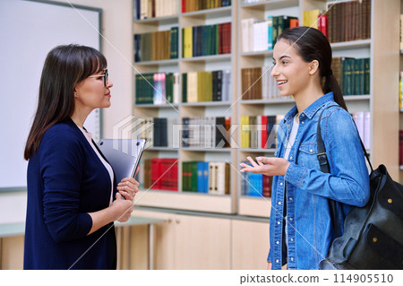 Female teacher talking to teenage girl high school student, inside educational building 114905510