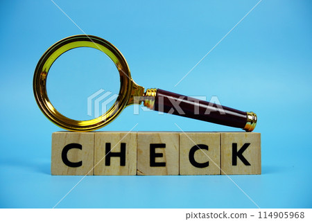 Check with wooden blocks alphabet letters and Magnifying glass on blue background 114905968