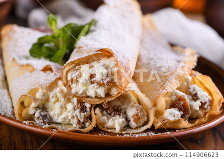 Thin pancakes stuffed with cottage cheese, honey and raisins 114906623