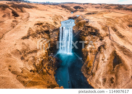 Powerful Skogafoss waterfall flowing with dry mountain in autumn at Iceland 114907617