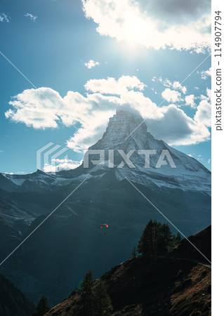 Matterhorn mountain with tourist playing parachute on blue sky in daylight at Switzerland Matterhorn mountain with tourist playing parachute on blue sky in daylight at Switzerland 114907794
