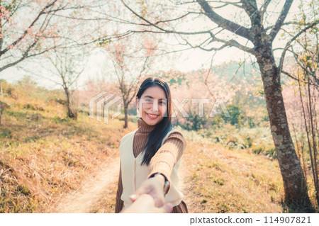 Young asian woman holding hands with her boyfriend enjoying in wild himalayan cherry blooming in springtime 114907821