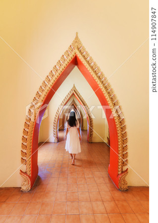 Asian woman walking in traditional golden arch door with Thai style carve in corridor at Wat Tham Sua 114907847