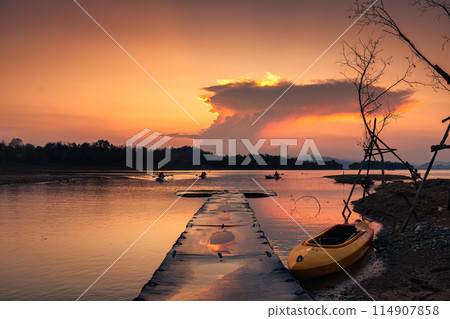 Sunset view of the Kaeng Krachan reservoir with fishing boat and tourist rowing canoe Sunset view of the Kaeng Krachan reservoir with fishing boat and tourist rowing canoe 114907858
