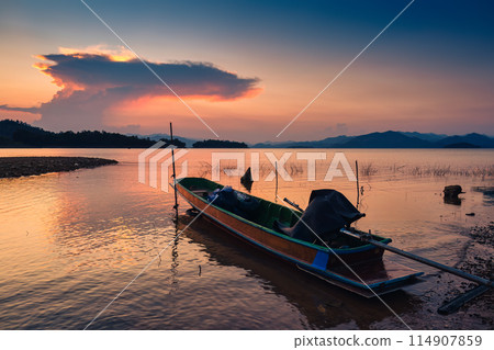 Sunset view of the Kaeng Krachan reservoir with fishing boat and tourist rowing canoe Sunset view of the Kaeng Krachan reservoir with fishing boat and tourist rowing canoe 114907859