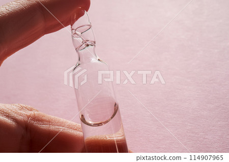 Ampoule for injection with medicines on a pink background in hand. Ampoule for injection with medicines on a pink background in hand. 114907965