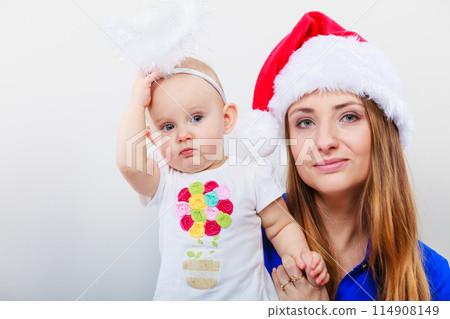 Mother wearing santa hat holding baby 114908149