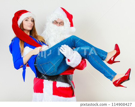 Santa Claus holding woman with christmassy hat Santa Claus holding woman with christmassy hat 114908427
