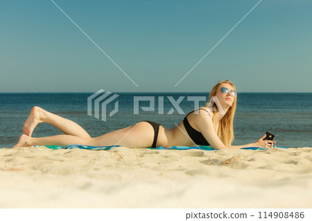 Woman in bikini sunbathing and relaxing on beach 114908486