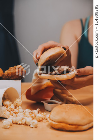 fast food, people and unhealthy eating concept - close up of woman hands holding hamburger or cheeseburger fast food, people and unhealthy eating concept - close up of woman hands holding hamburger or cheeseburger 114909295