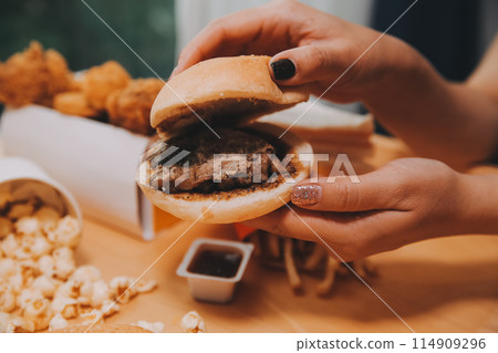 fast food, people and unhealthy eating concept - close up of woman hands holding hamburger or cheeseburger 114909296