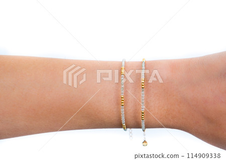 Beautiful woman wrist wearing aventurine stone bracelets set against white background. Beautiful woman wrist wearing aventurine stone bracelets set against white background. 114909338