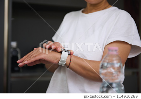 Cropped view of woman's hands checking smart wrist watch. Fitness app, mobile app. People. Health care and modern wireless technology 114910269