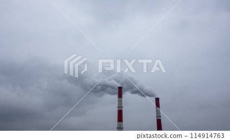 Smoke and steam from the pipes of a thermal power plant against a cloudy sky. 114914763