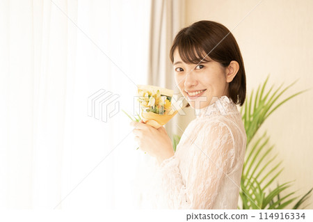 拿著迷你花束的微笑的女人 拿著迷你花束的微笑的女人 114916334