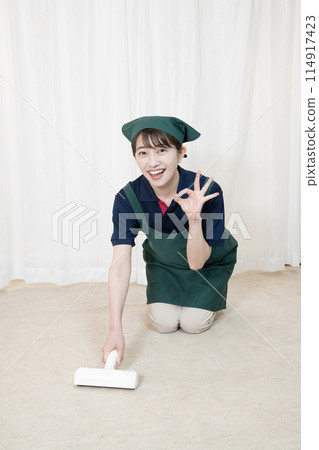 A female housecleaning worker cleaning with a carpet cleaner 114917423
