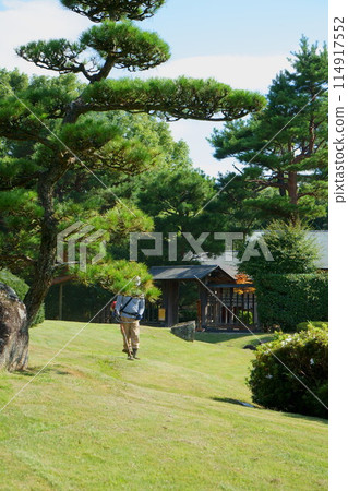 A craftsman mowing the lawn of a Japanese garden 114917552